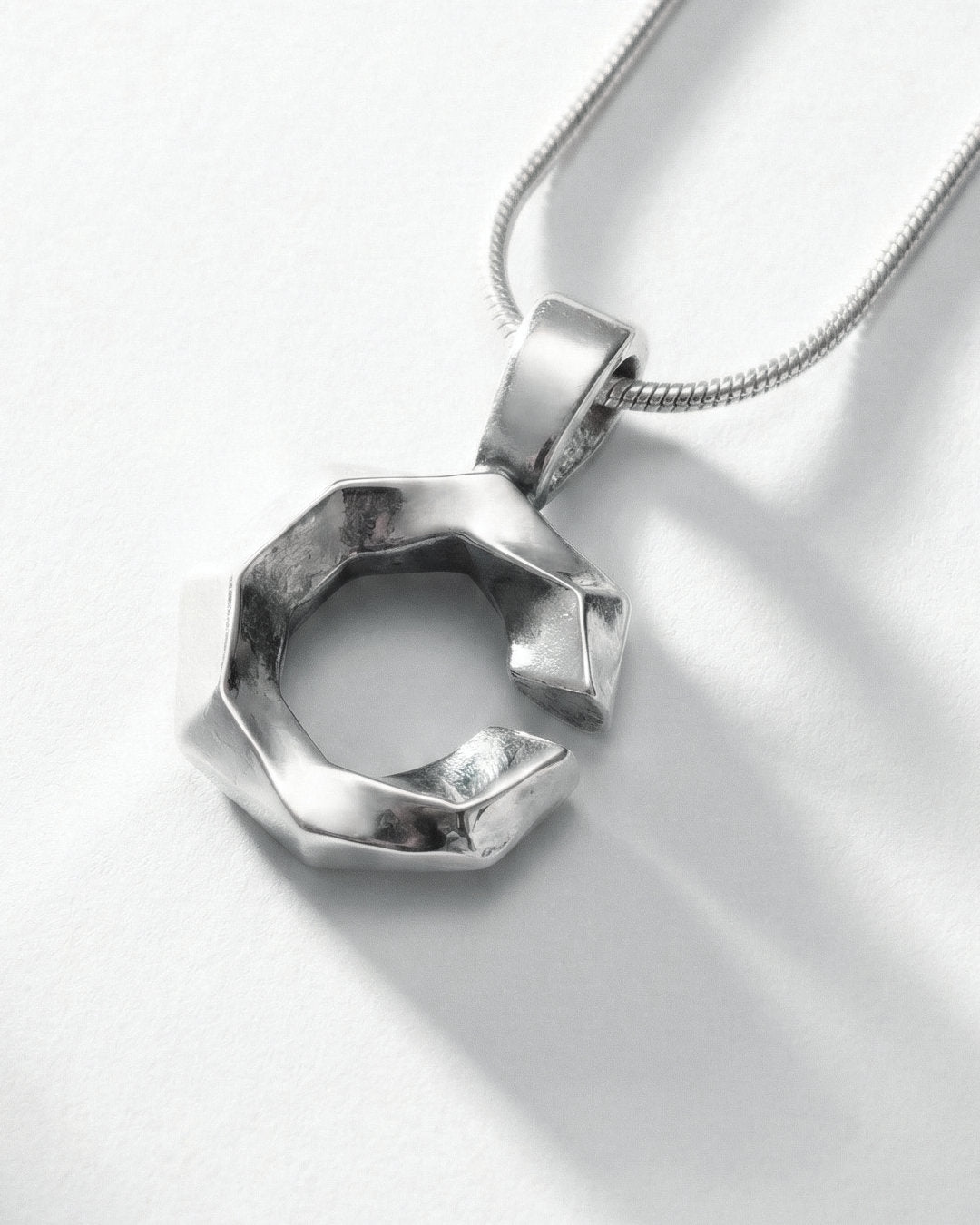 Silver geometric letter C pendant on a white background