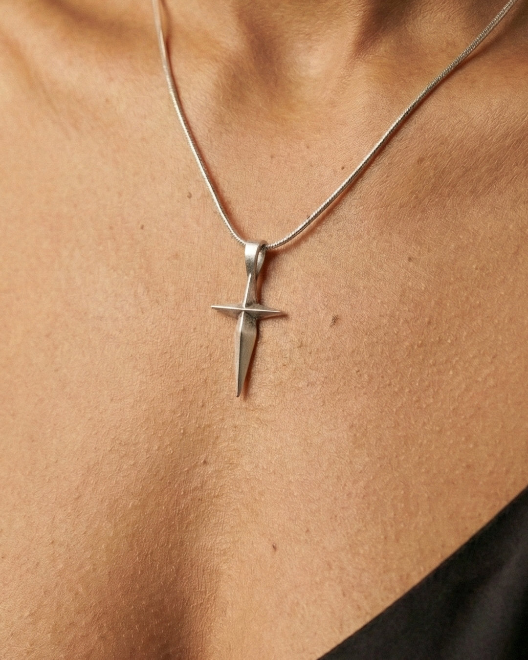 Silver cros pendant on a person's neck