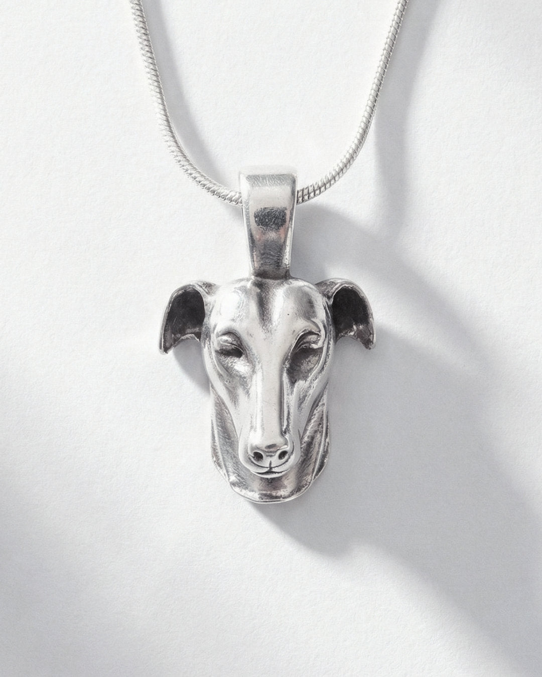 Silver pendant of a Galgo dog head on a white background